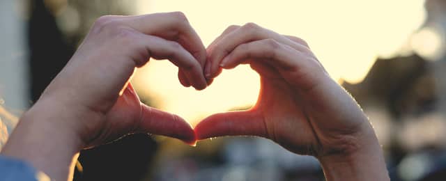 Hands cupped to make a heart in the sunlight.