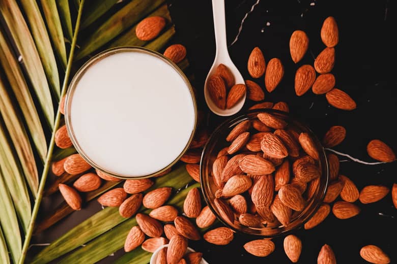 Almond milk with almonds and palm leaf.