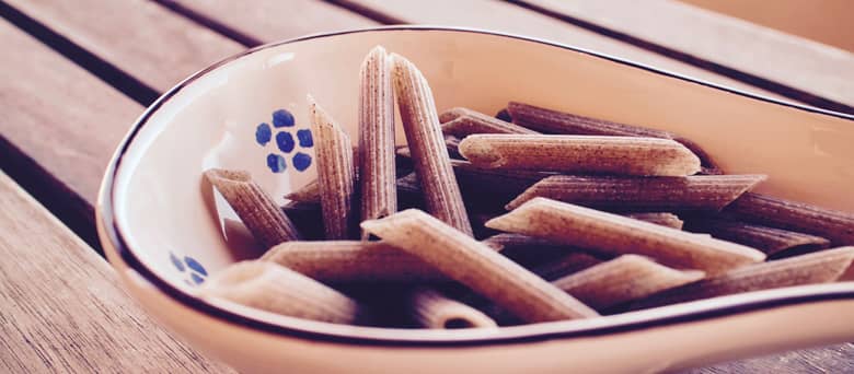 A spoon of uncooked buckwheat penne pasta.