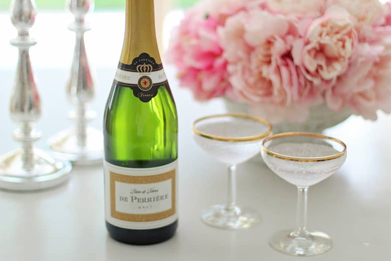 A bottle of champagne with saucers and flowers.