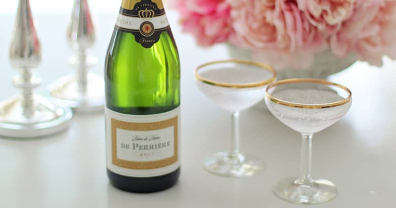 A bottle of champagne with saucers and flowers.