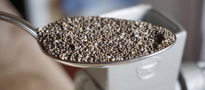 Chia seeds on a spoon with scales in the background.