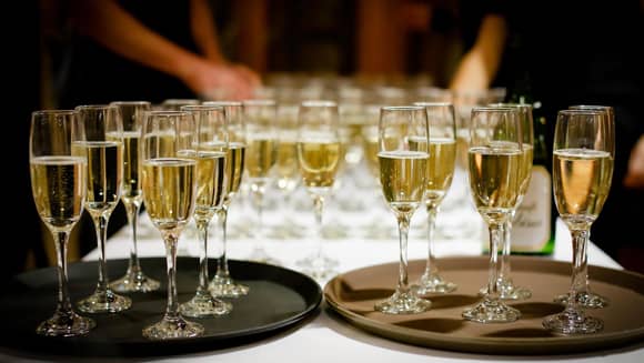 Reception champagne glasses with guests in the background.