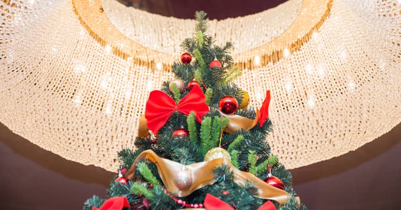 Illuminated Christmas tree beneath a stunning chandelier.