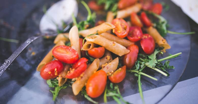 Vegetarian pasta meal on a dish with spoon.