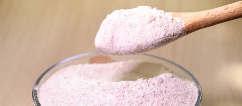 A bowl of flour with wooden spoon.