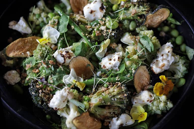 A healthy meal of vegetables, feta, crumb, and flowers.