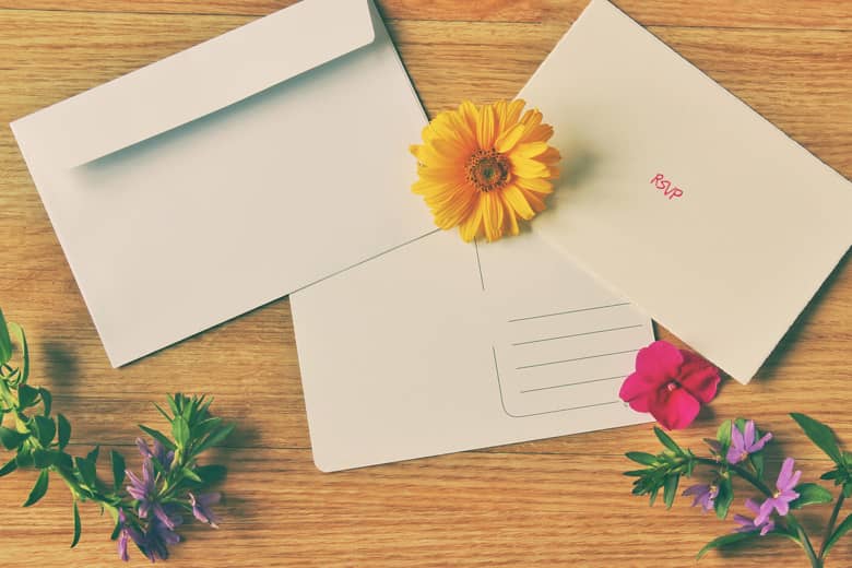 An RSVP invitation and envelope on a desk with flowers.