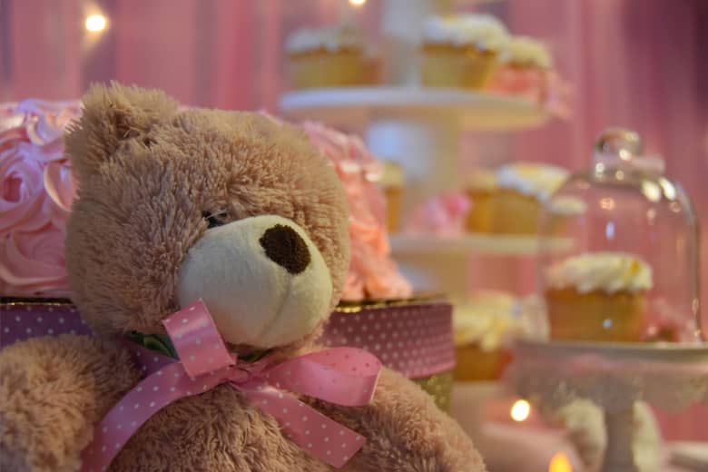 Pink baby shower cakes with teddy bear in the foreground.