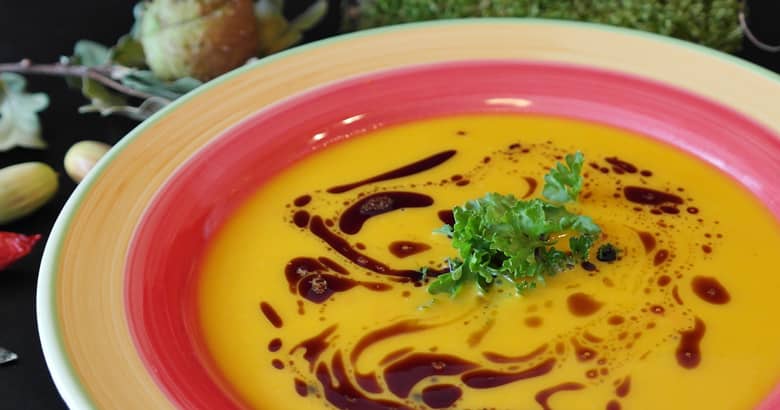A colourful bowl of pumpkin soup.