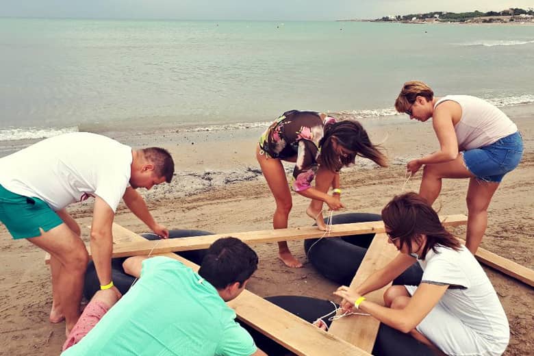 Mixed teambuilding exercise making a raft on a beach.