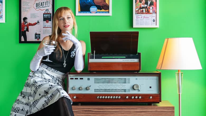 Retro woman with a glass of champane by an old record player.