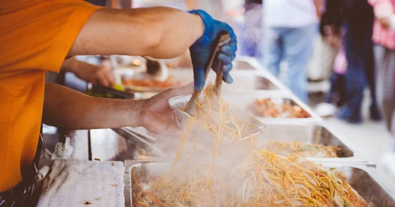 Street food stall with a chef serving up noodles.
