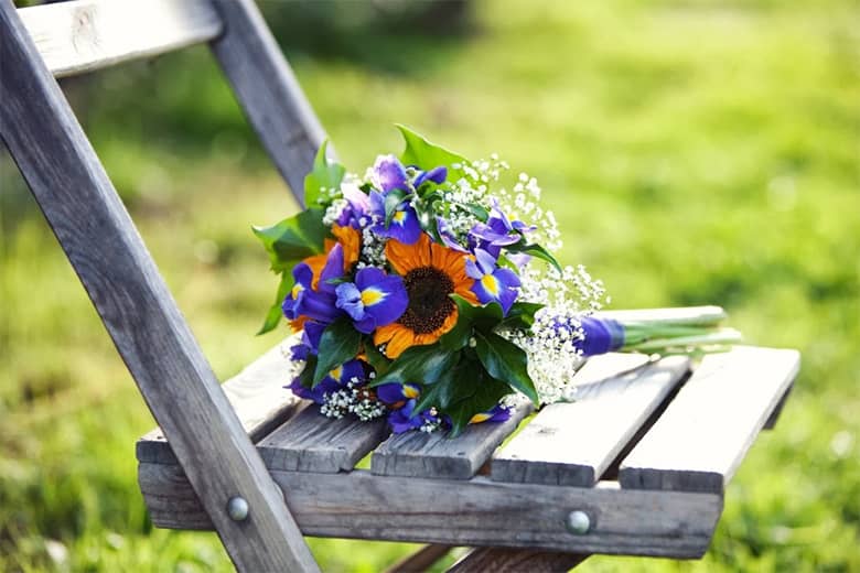 Summer wedding bouquet resting outside on a wooden chair.