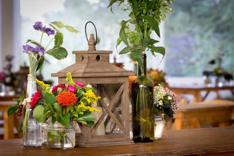 Table centrepiece by PenniBlack with lantern and fresh wild flowers in jars.
