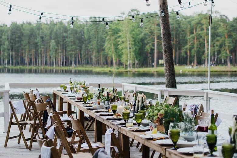 Outdoor tables set for dining by a lakeside.