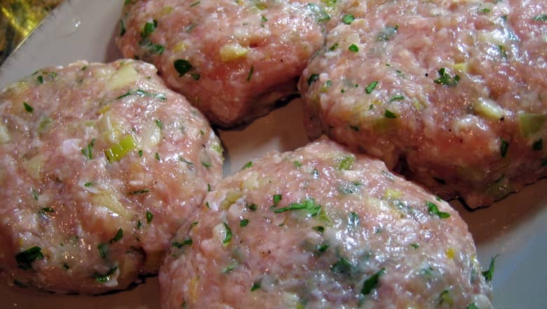 A plate of 4 uncooked turkey burgers.