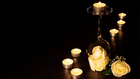 Tea light candles on an upturned wine glass with petals.
