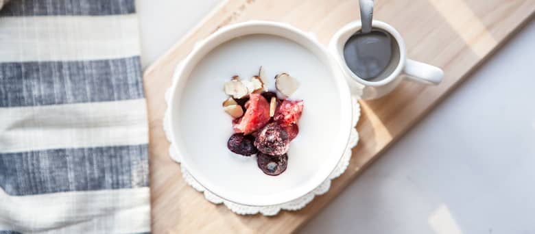 A bowl of yoghurt with fruit and nuts.