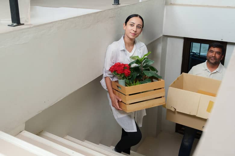People carrying boxes and plants up stairs.