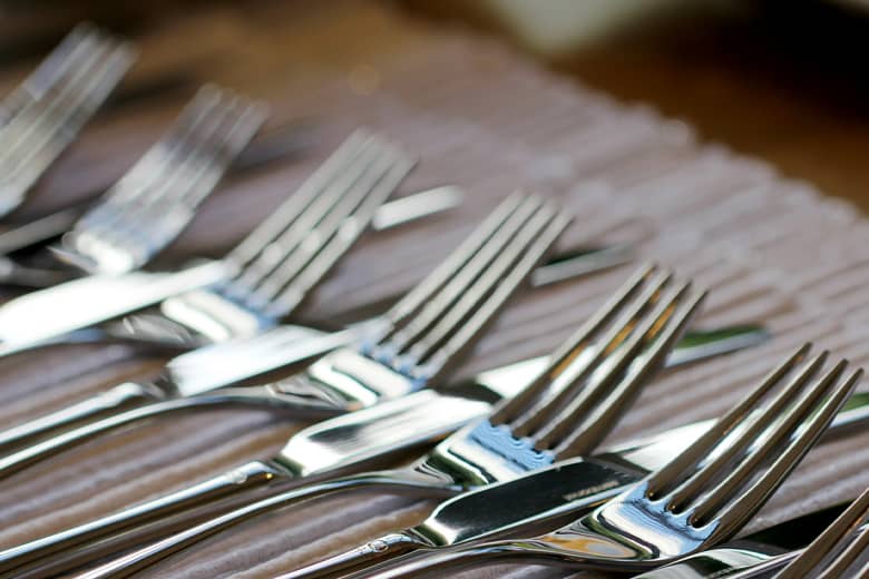 Stainless steel forks and knives on brown wooden table