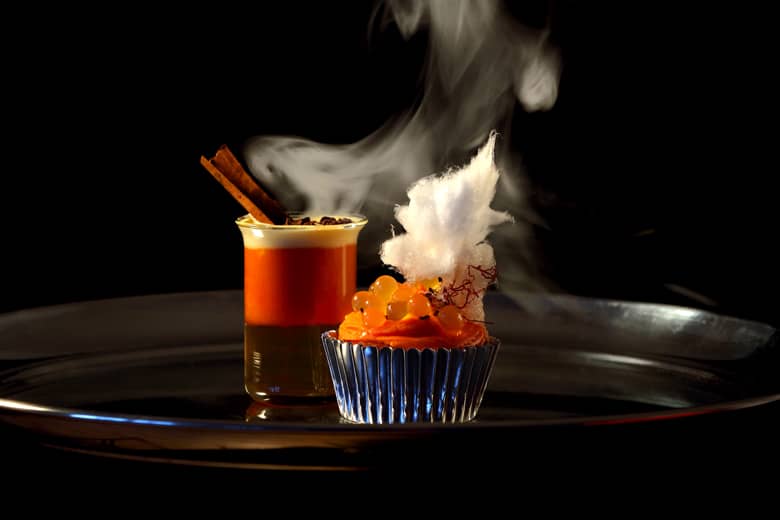 Cocktail and cake on a silver tray.