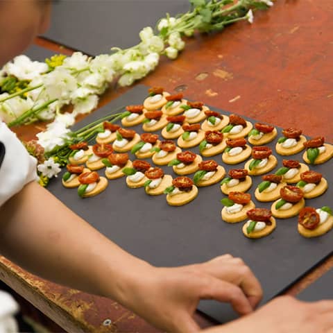 Chef preparing parmesan shortbread with goat’s cheese, cherry tomatoes & red onion marmalade canapés.