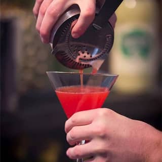 Bartender pouring a freshly mixed cocktail.