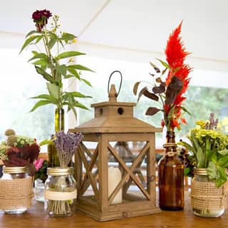 Themed table centerpieces with lantern, and upcycled jars of wild flowers.