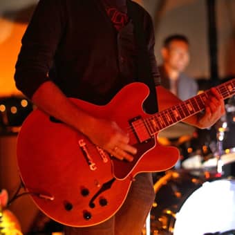 Band guitarist playing with the drummer in the background.