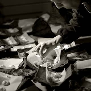 Chef dressing bark platters with micro leaves.