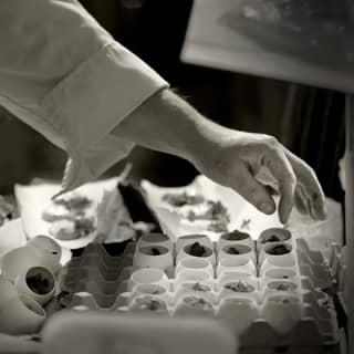Chef carefully preparing the egg shells filled with pumpkin mousse and truffle foam.