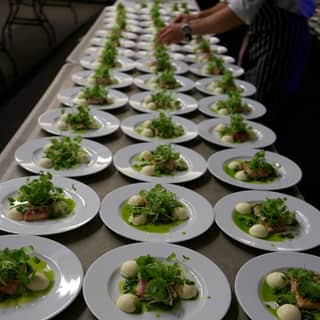 Plates of confit salmon starters getting their finishing touches.