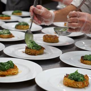 Chefs preparing the crisp root rosti with creamed spinach main course.