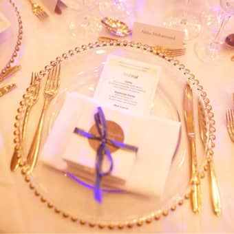 Table setting with gold beaded charger plates, favour box, and menu.