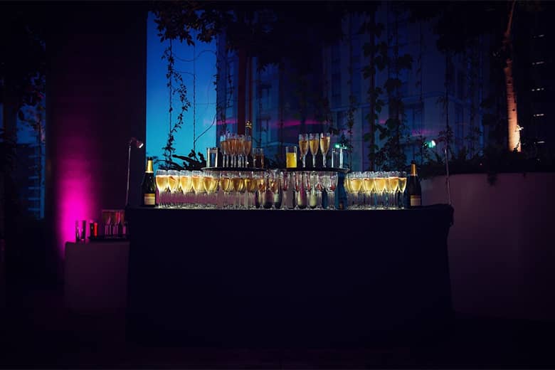 Illuminated drinks table with glasses of Champagne, juice and wine.