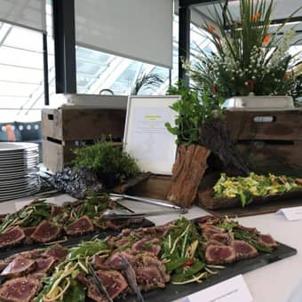 Buffet table setup with hot and cold options, plates, and themed floral decorations.