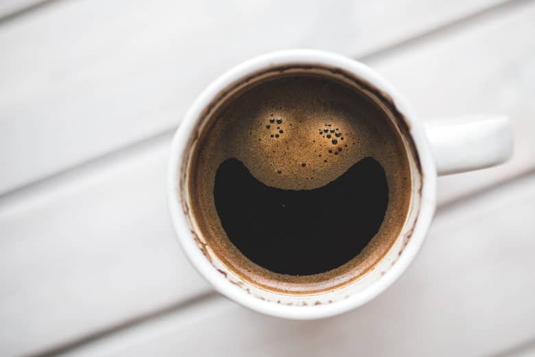 White coffee cup where the drink looks to be smiling.