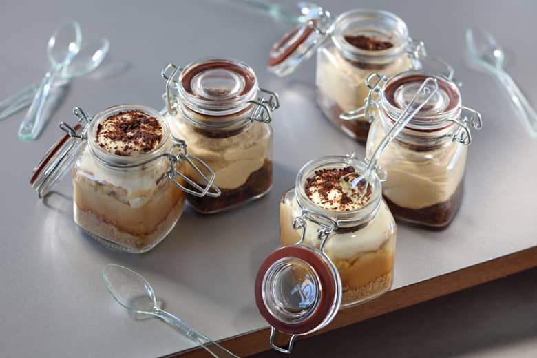 Five mini dessert pots with spoons.