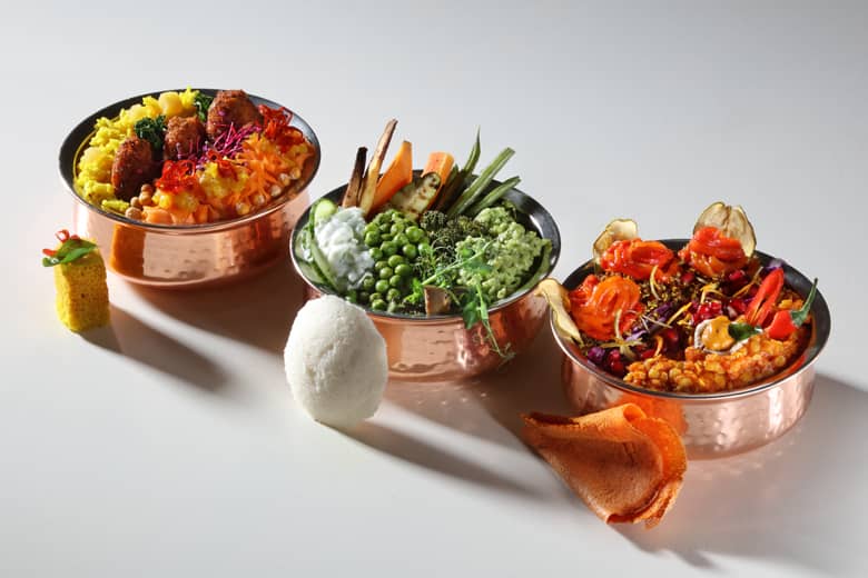 Three small copper dishes representing the three doshas, filled with vibrant food.