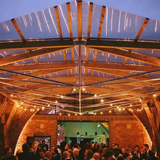 The Timber Pergola illuminated at night with guests mingling.