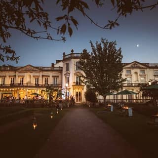 Front of Grove House at dusk illuminated with candles and terrace lighting.