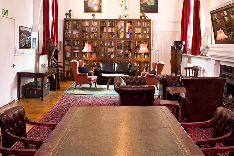 The Club Room with boardroom table, bookshelves and armchairs.