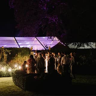 Wedding guests mingling outside the marquee in the evening.