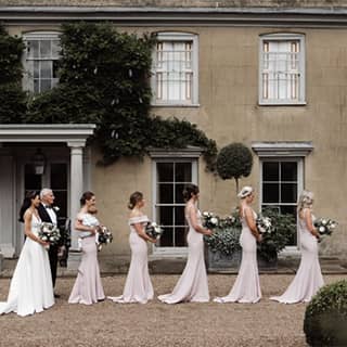 Bride and father with bridesmaids outside the manor house.